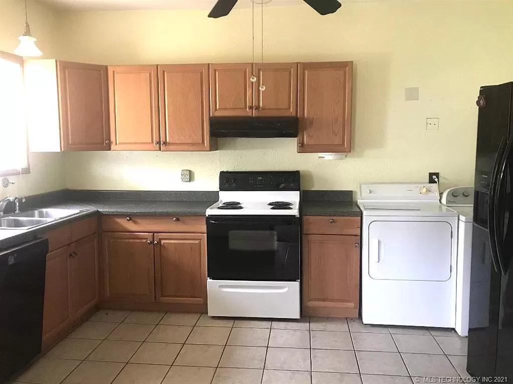 The kitchen in 2021 — electric range, dishwasher at the left of the sink, fridge at the end, washer and dryer in the alcove.